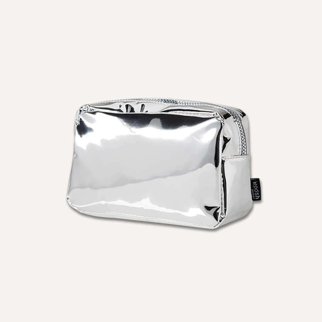 Angled view of the Woosh Beauty silver essential medium makeup bag