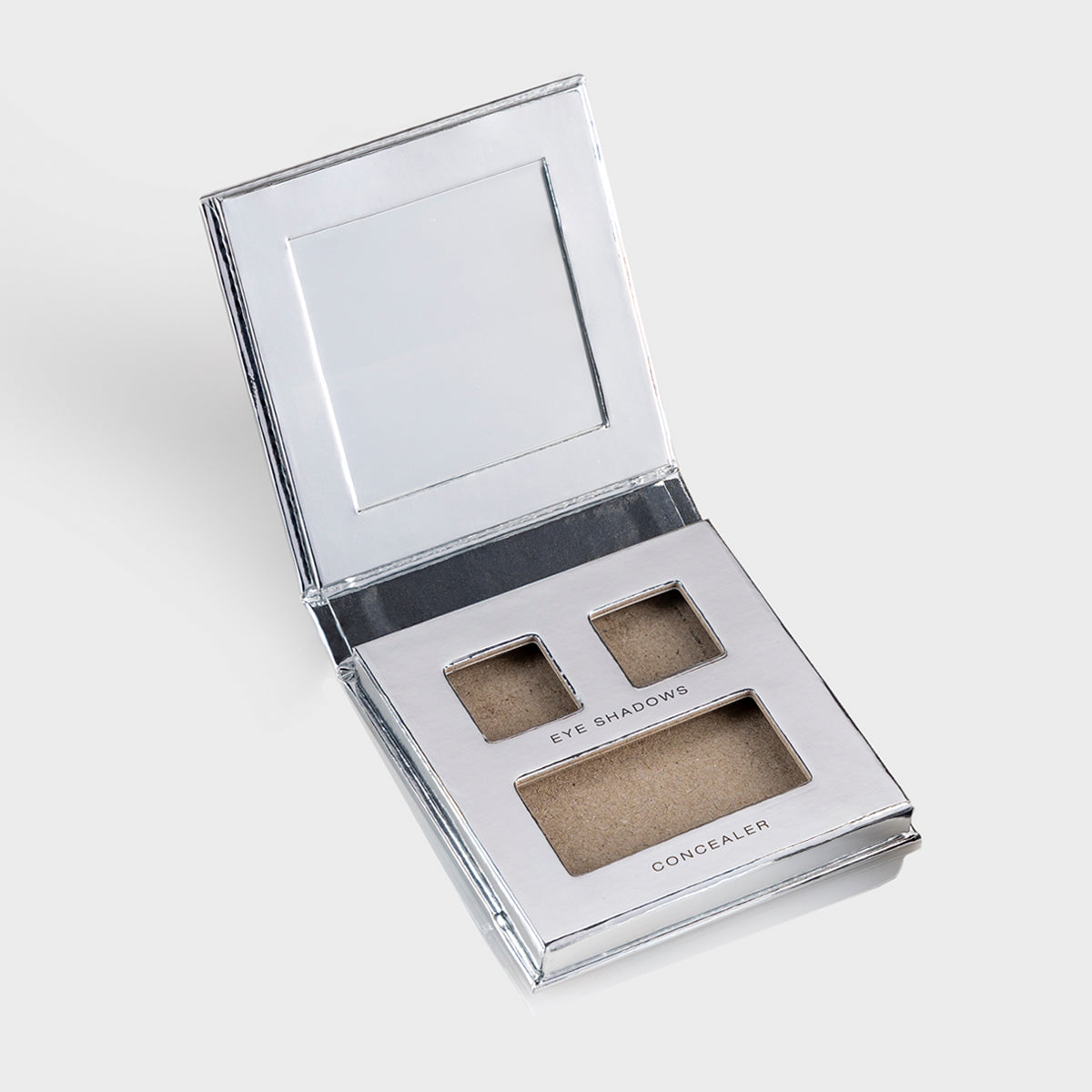 a photo of an empty silver makeup palette with mirrored flap and slots for 2 eye shadows and 1 concealer