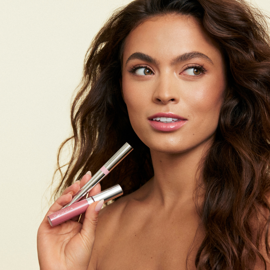 Image of model holding up the duo with spin on gloss in hint and monogamous stain linger. Model has bottles near face with products applied to lip