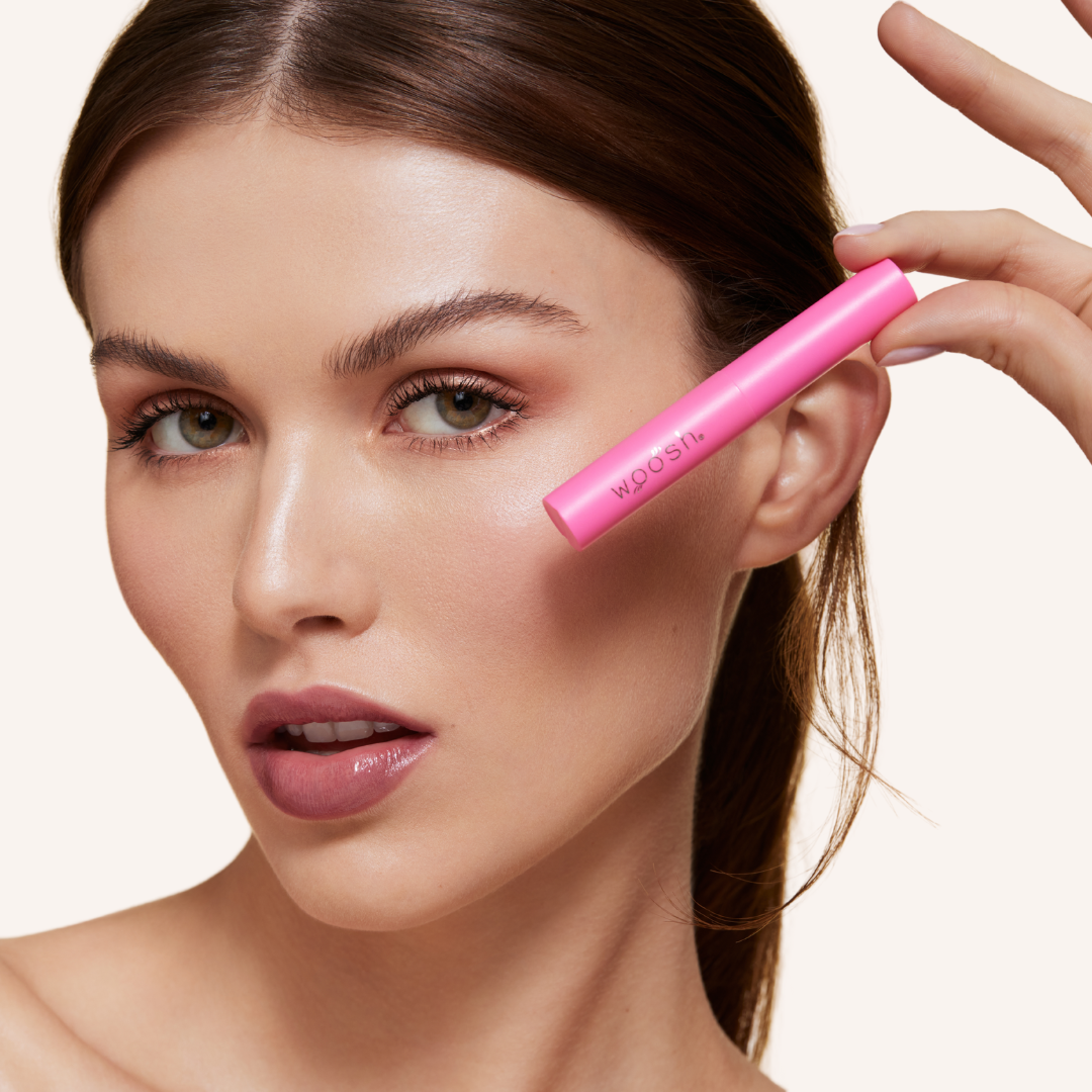 Mascara tube held close to face to show petite sizing