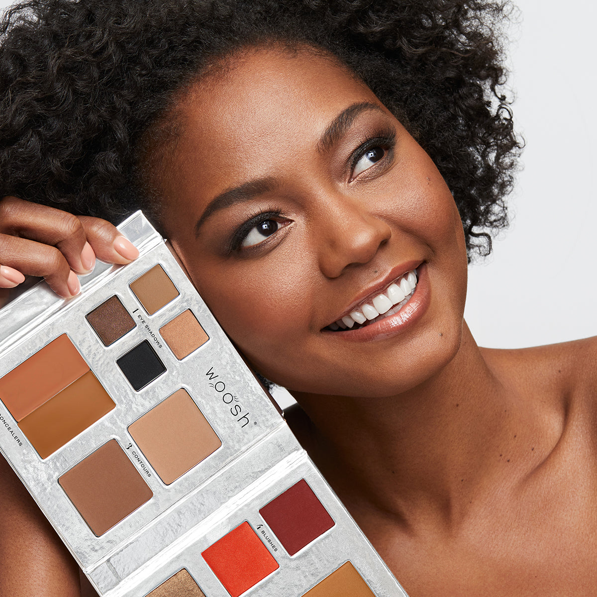Brunette model holding the 13 pan Fold out Face palette that includes Eyeshadow, cream concealer, contour, blush, highlight, and foundation powders.