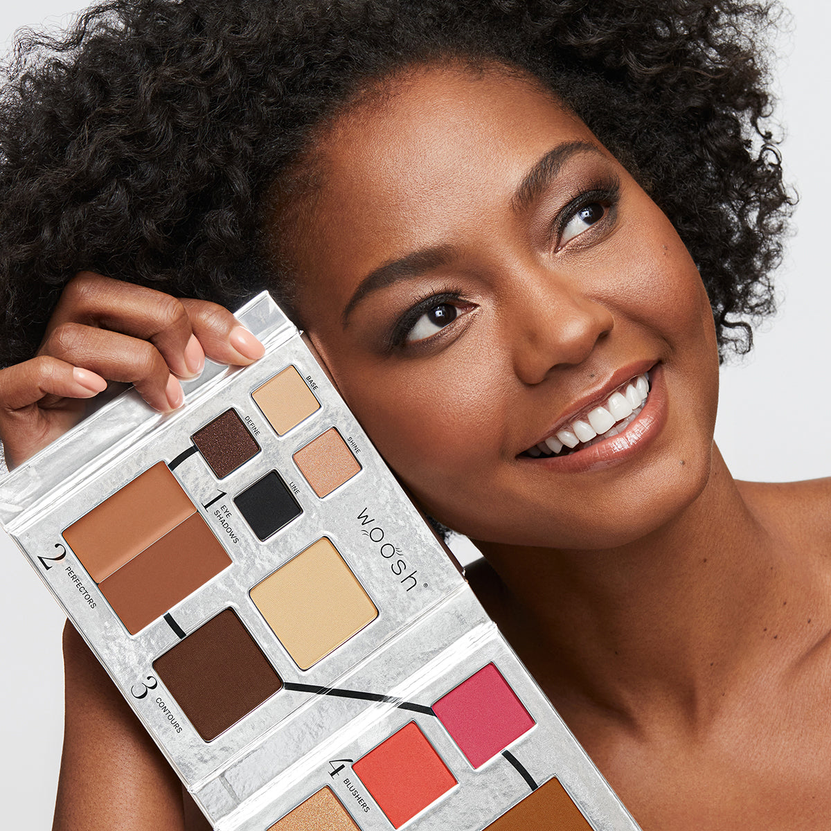 Brunette Model holding the 13 pan Fold out Face palette that includes Eyeshadow, cream concealer, contour, blush, highlight, and foundation powders.