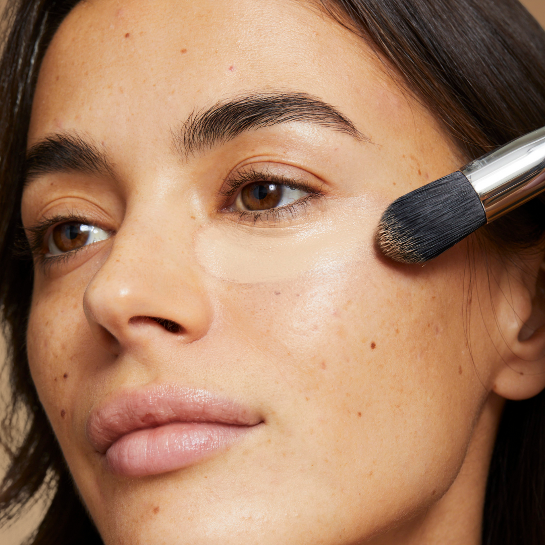 model applying concealer to under eye