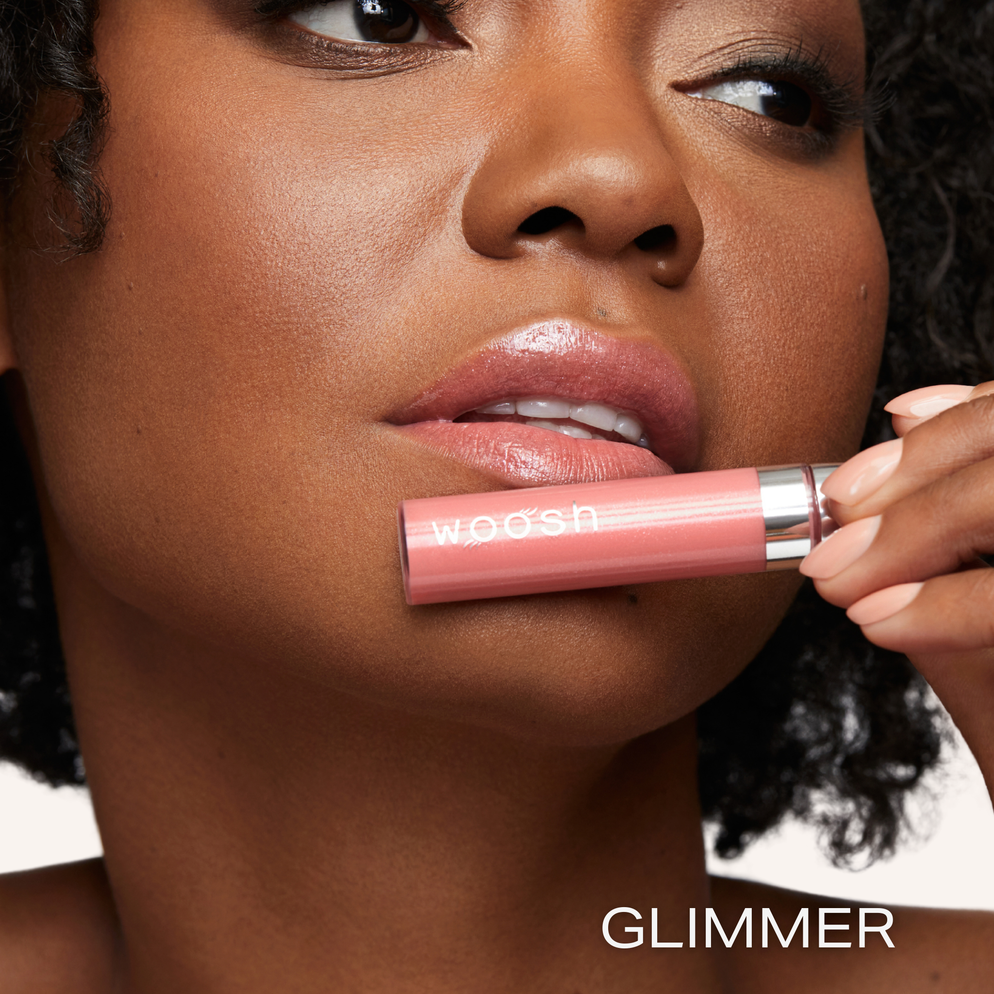Previously known as glam peach, glimmer is now infused with shea butter and hyaluronic acid. The perfect peach shade with sparkles. Photo of model holding bottle close to lip.