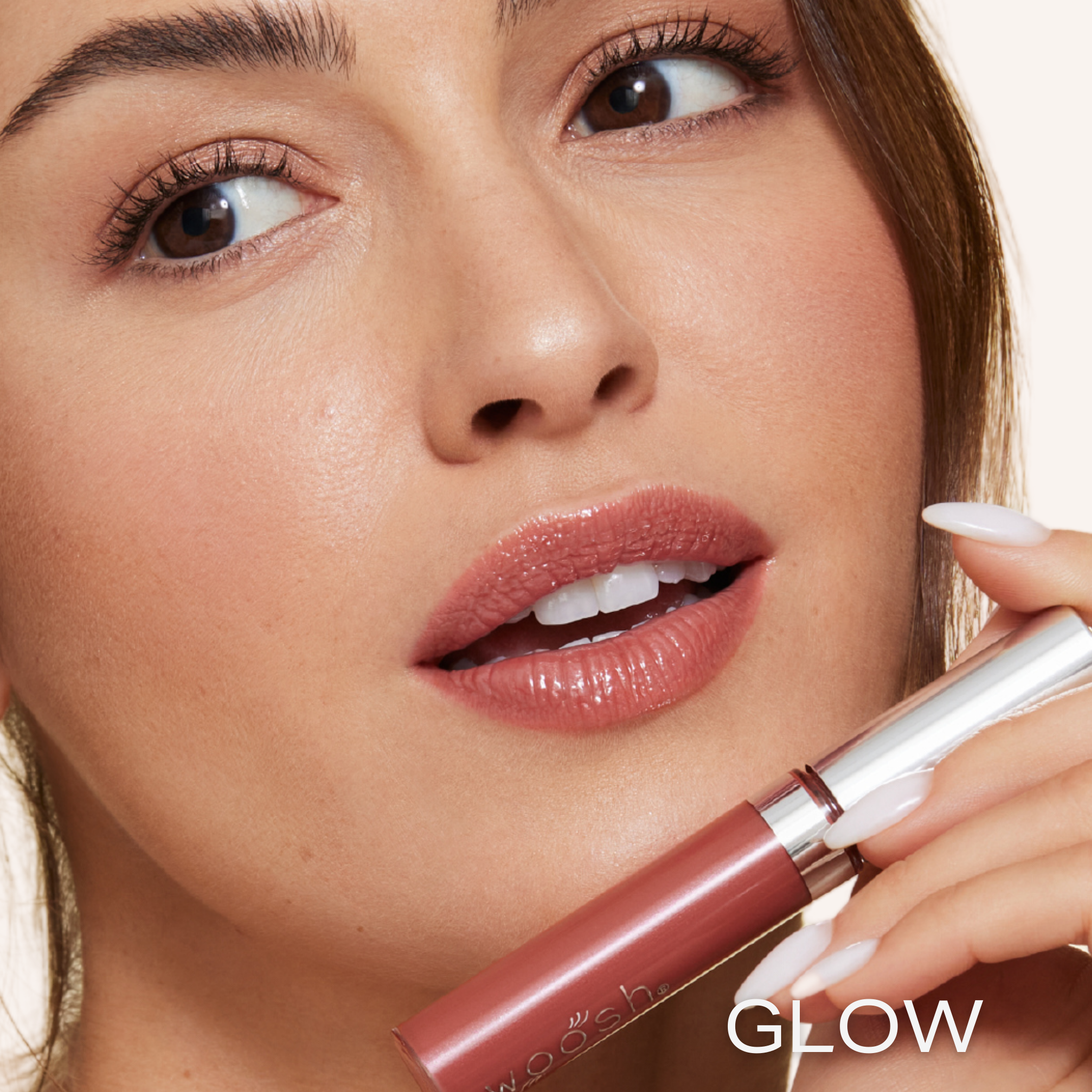 Previously known as Rich Copper, our favorite lip gloss has been renamed to Glow. Now infused with shea butter AND hyaluronic acid. Photo of model holding gorgeous brown nude color to lips