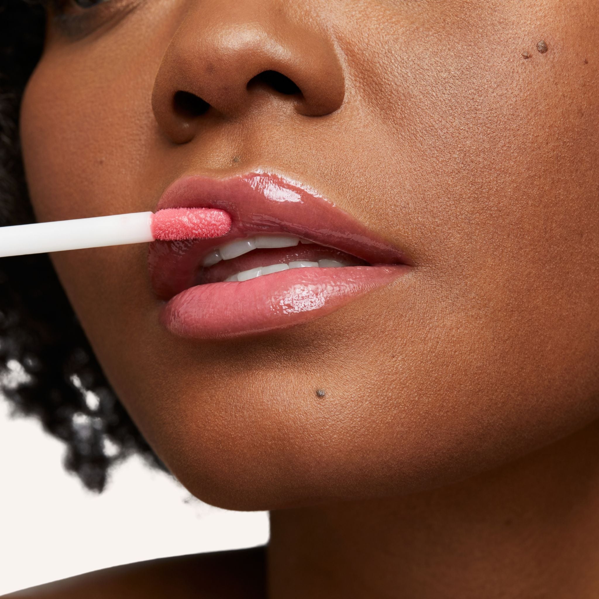 Previously known as pink natural, pop is now infused with shea butter and hyaluronic acid. The perfect pink pop of color shade. Photo of model applying gloss to lip