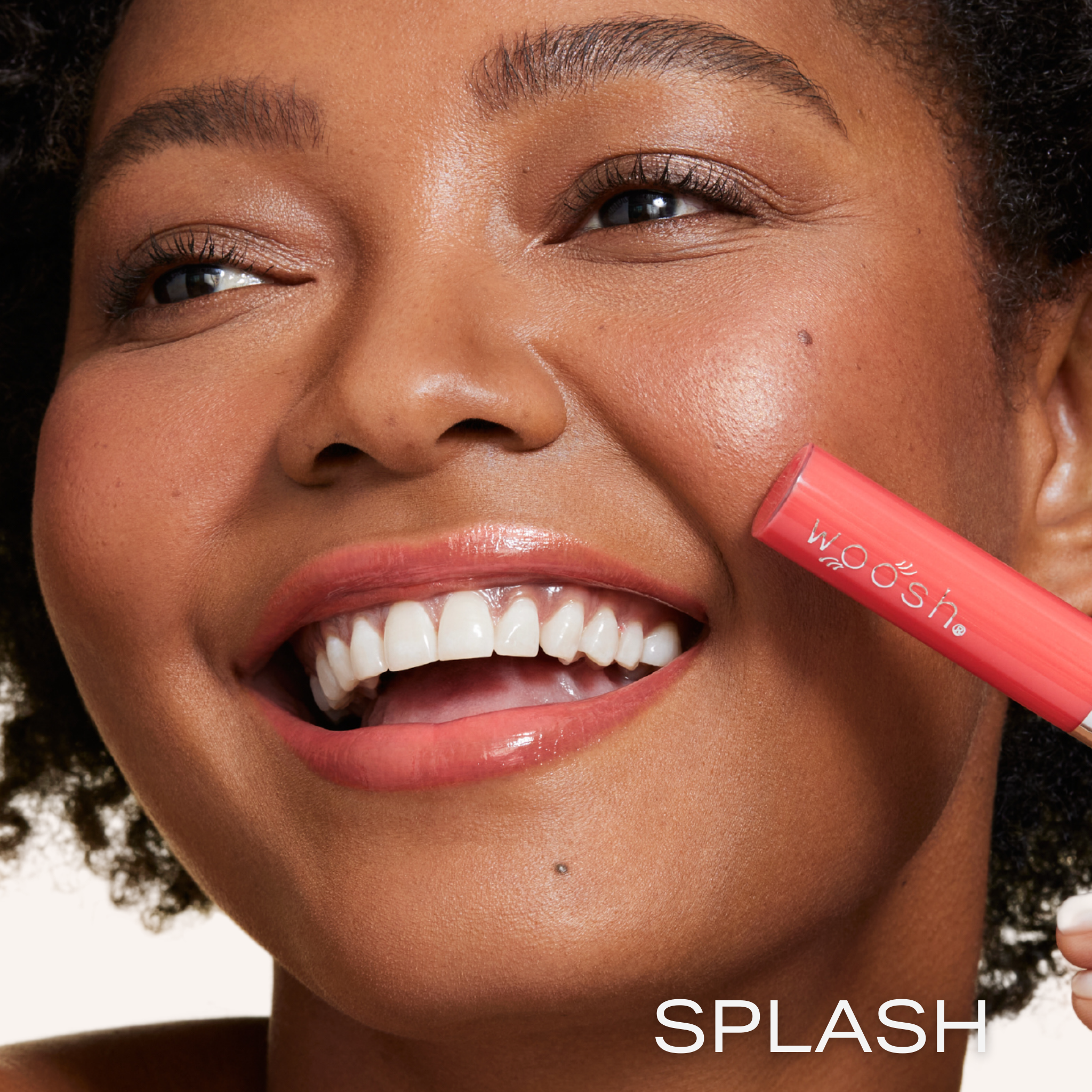 New shade splash is a bright coral shade infused with shea butter and hyaluronic acid. . closeup shot of model holding bottle close to lip