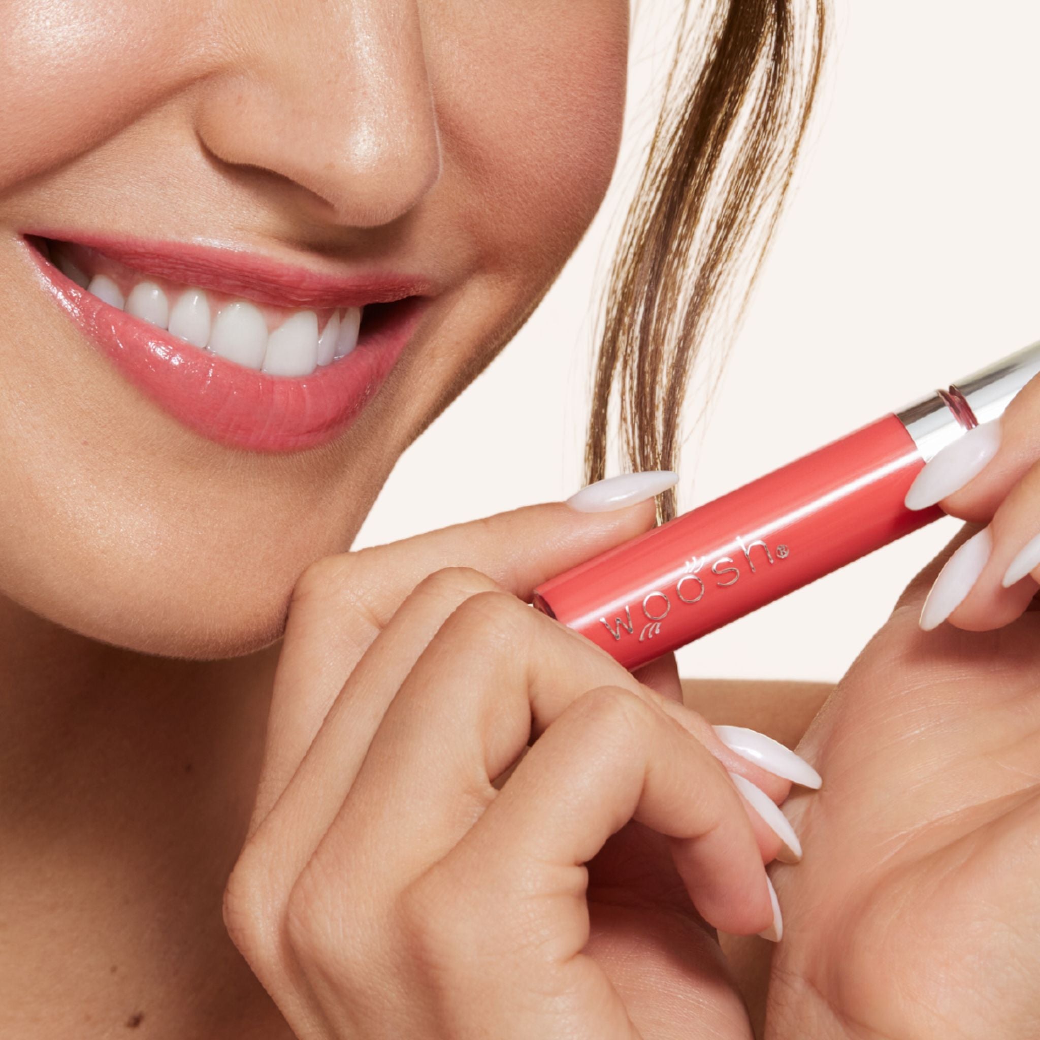 New shade splash is a bright coral shade infused with shea butter and hyaluronic acid. . closeup shot of model holding bottle close to lip