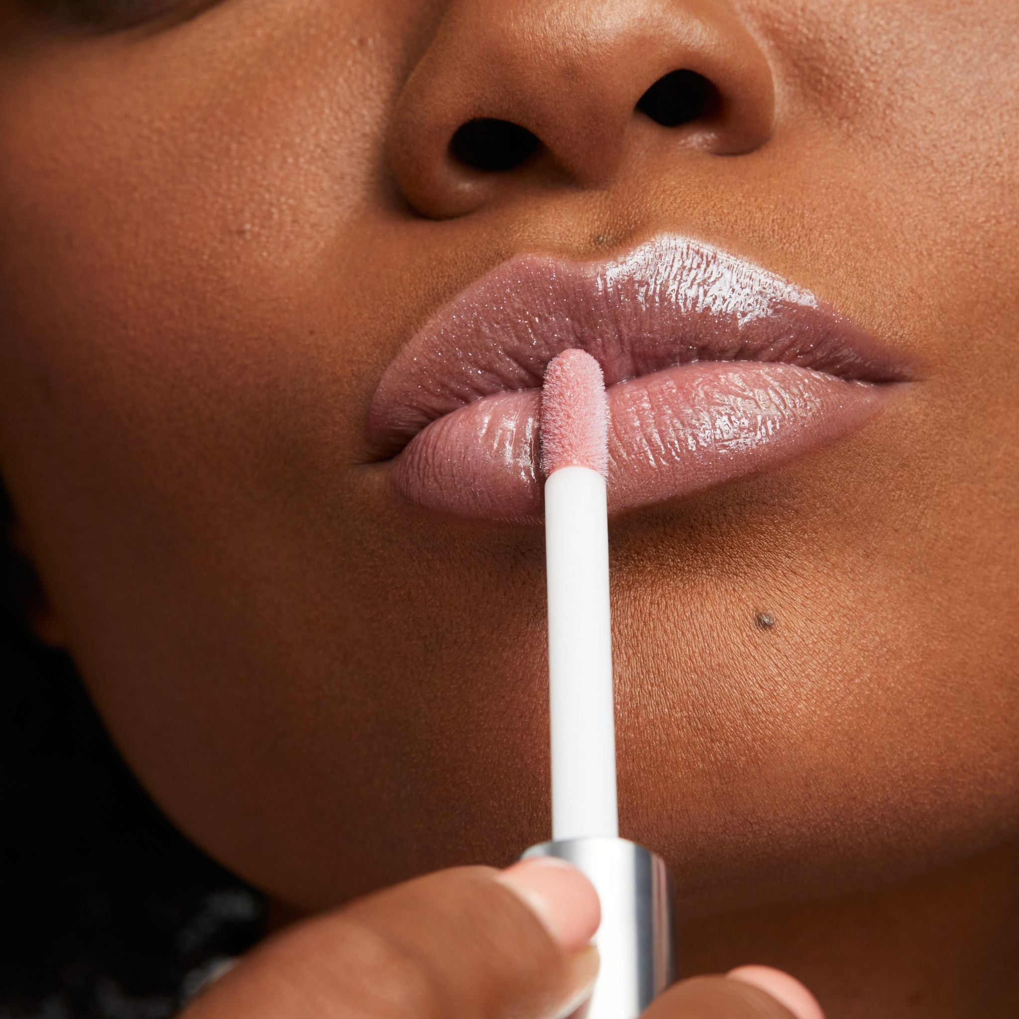 Previously known as beige frosted, our favorite lip gloss has been renamed to veil. Now infused with shea butter AND hyaluronic acid. Photo of model applying gorgeous nude color to lips