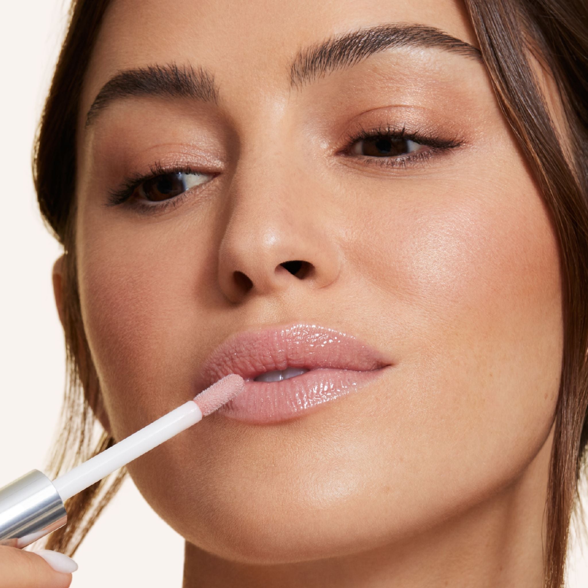 Previously known as beige frosted, our favorite lip gloss has been renamed to veil. Now infused with shea butter AND hyaluronic acid. Photo of model applying gorgeous nude color to lips