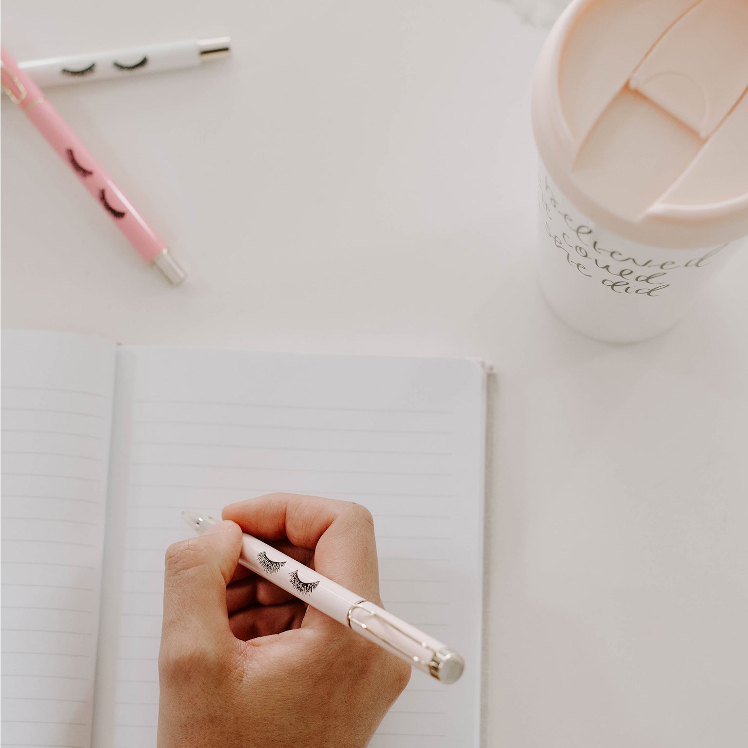 Hand writing with the white gold trimmed pen with eyelash detailing