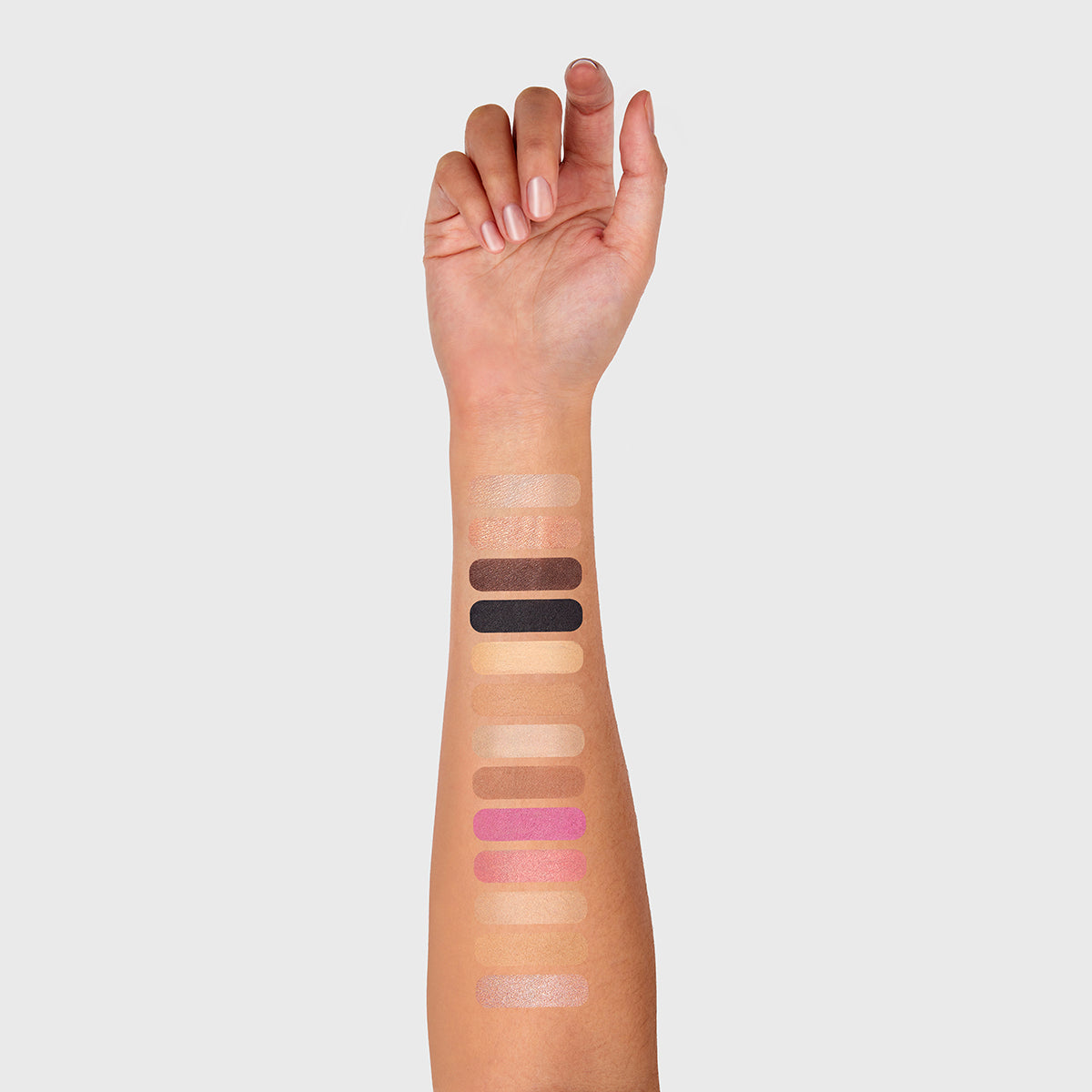 a photo of a light tanned woman's arm with 13 swatches showing all 13 cosmetics that are found in the fold out face #2.5 medium tan palette