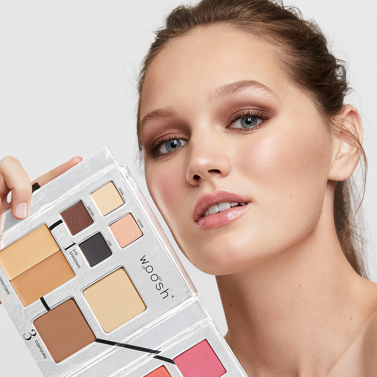a photo of a light-skinned model wearing beautiful, natural-looking makeup holding the Fold Out Face palette in shade #2 medium light