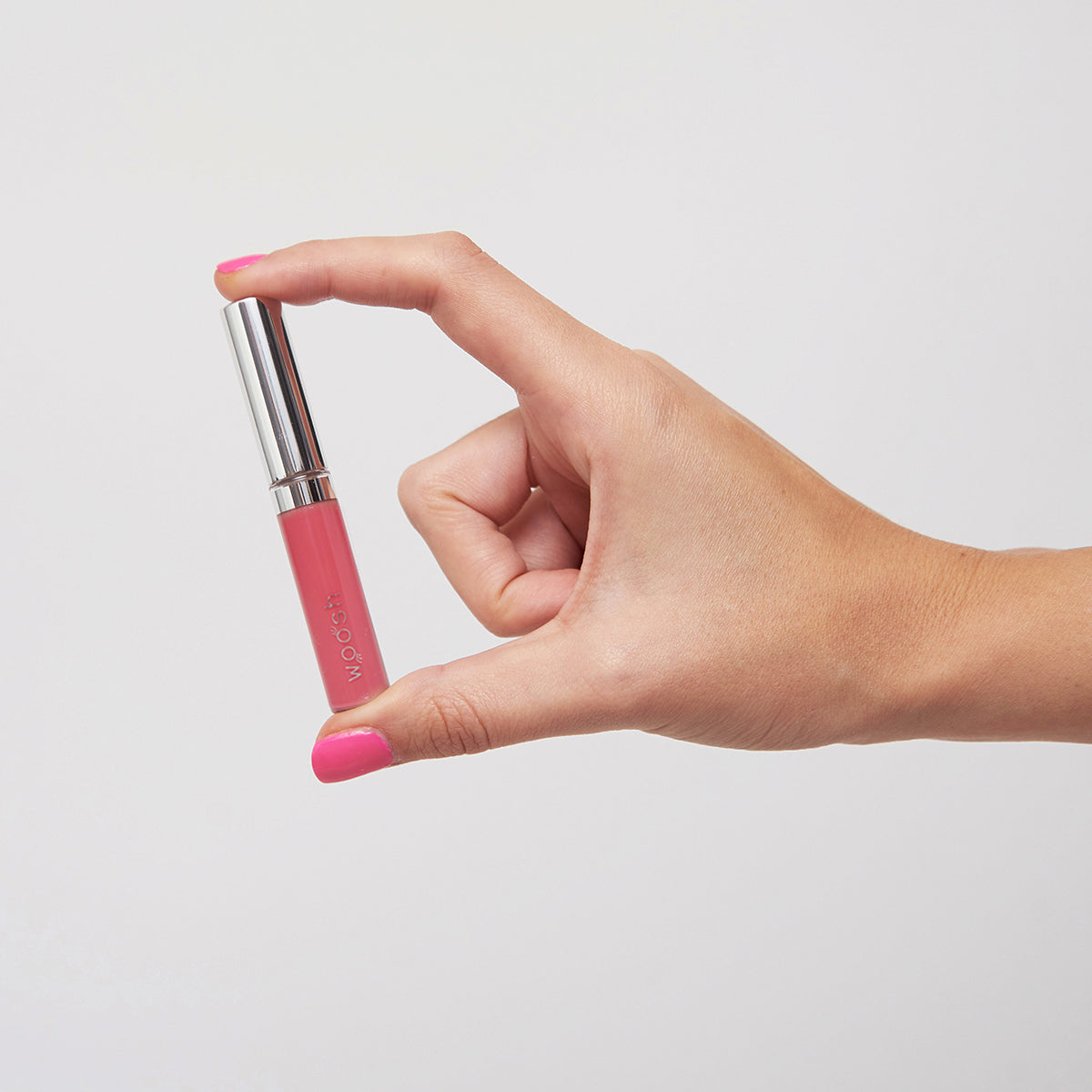 Model holding the Woosh Beauty pink natural mini lip gloss