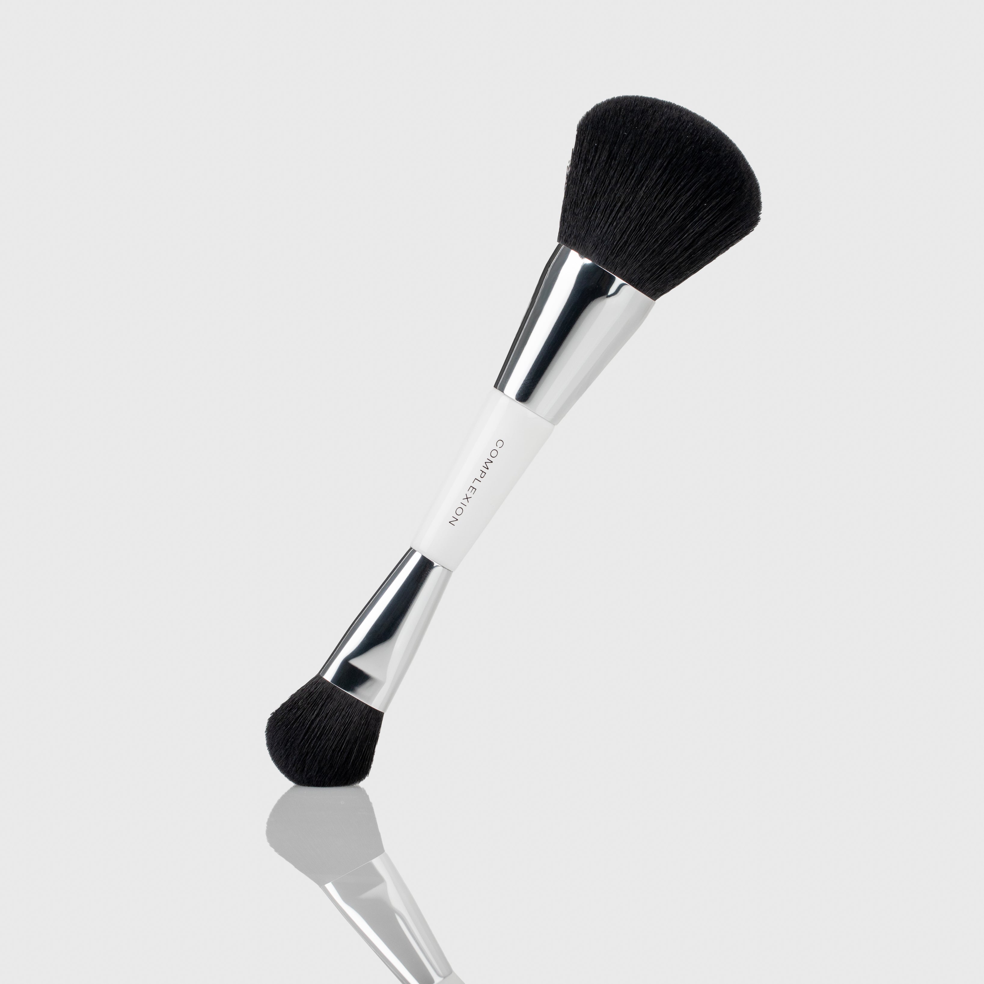 Two sided complexion foundation brush with one larger and densely packed head and one fluffy small end with silver accents
