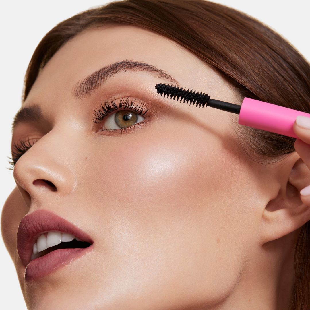 Close up image of model applying mascara. 