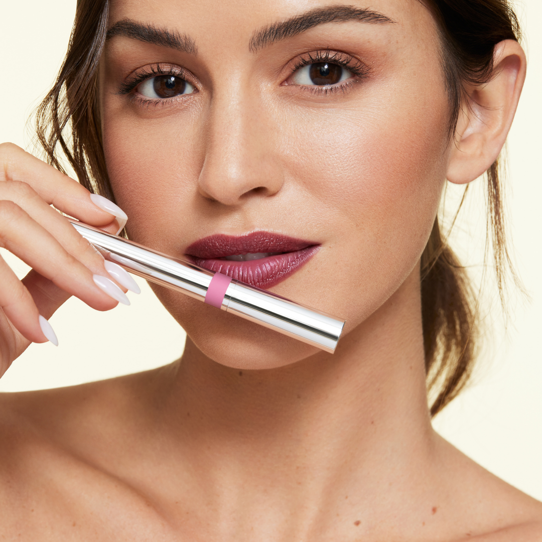 Fair skinned model with shade steadfast applied to lip. Holding silver Monogamous lip stain component. 