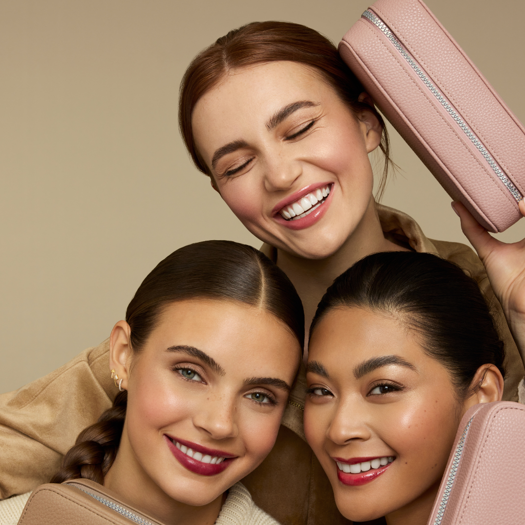 Image of 3 women holding out fold out cases in shades mauve and tan while smiling