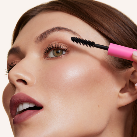 Close up image of model applying mascara 