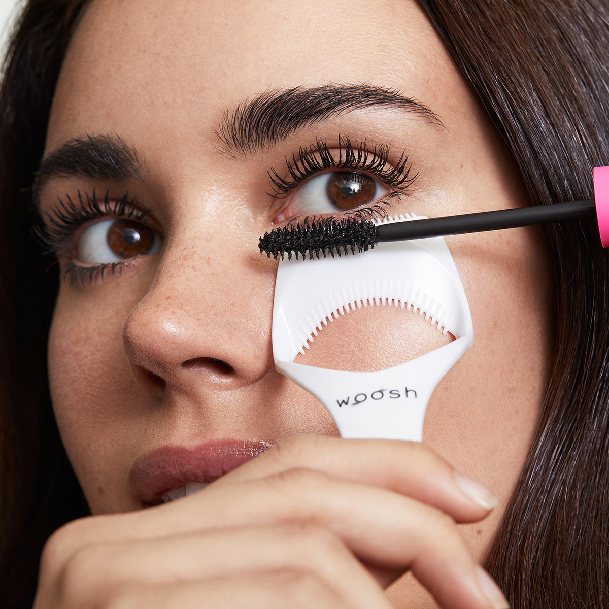 Model using the mascara shield to apply mascara to her lower lashes, protecting her skin from the mascara.