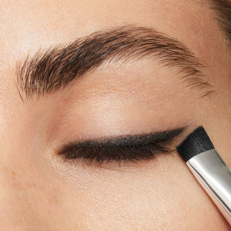 a photo of a pretty woman's closed eye with rich black powder lining the edge of the lid