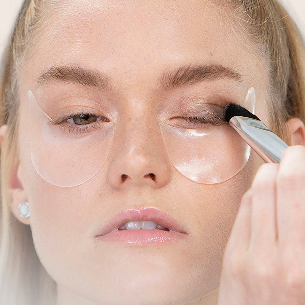 even eye stencils under eyes on model as she puts on her eyeshadow