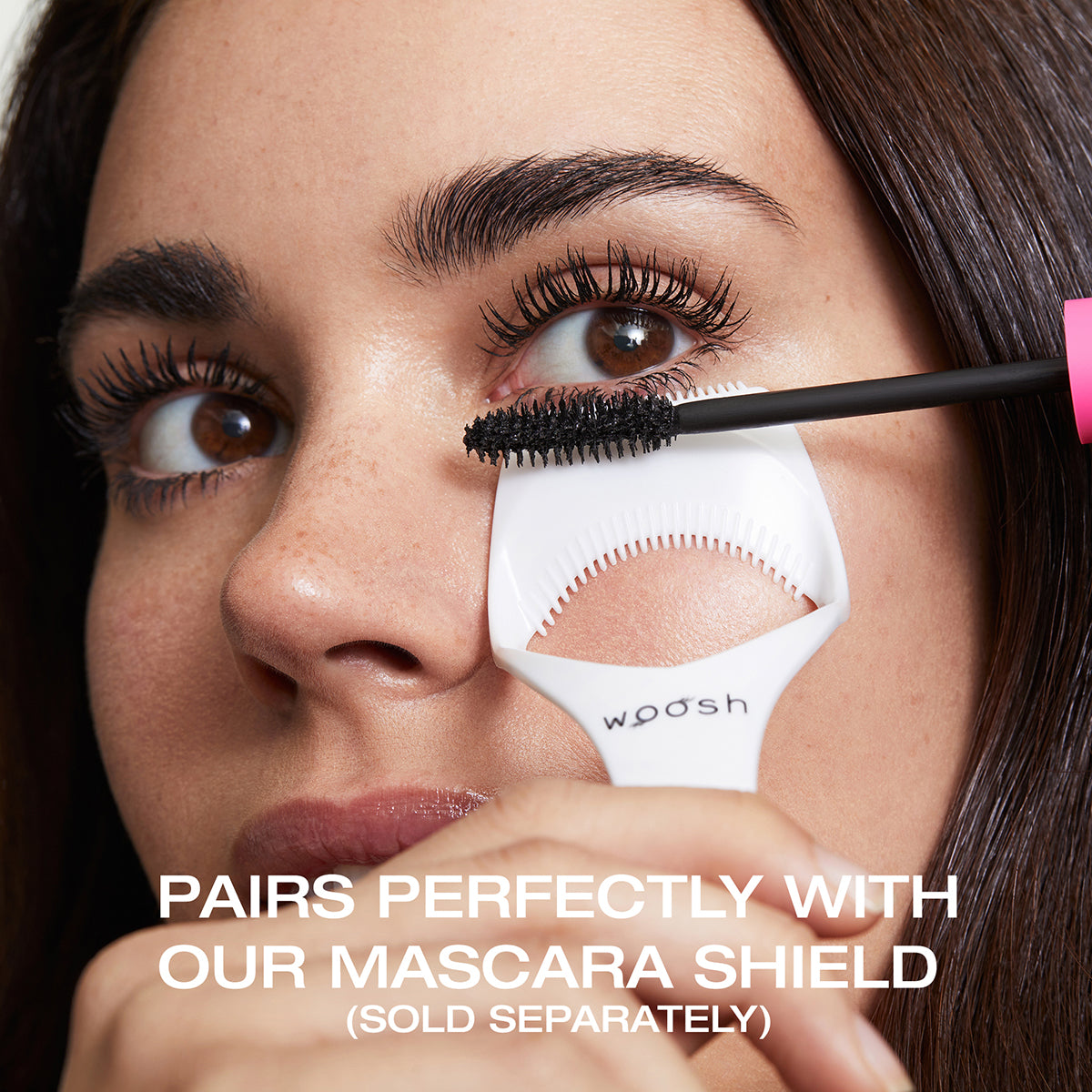  Woman using the mascara shield and mascara wand with text saying it pairs perfectly with our mascara shield (sold separately)