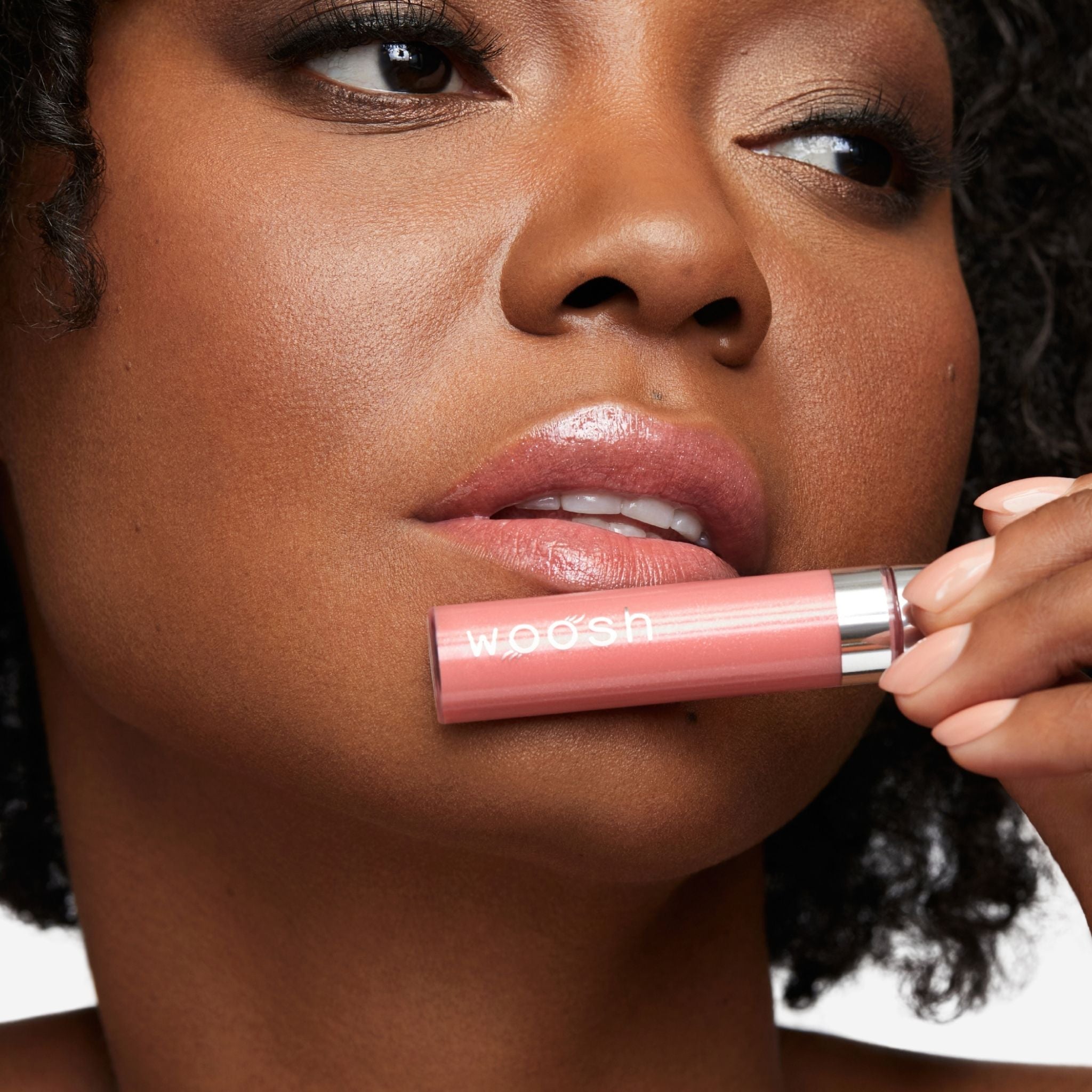 Previously known as glam peach, glimmer is now infused with shea butter and hyaluronic acid. The perfect peach shade with sparkles. Photo of model holding bottle close to lip.