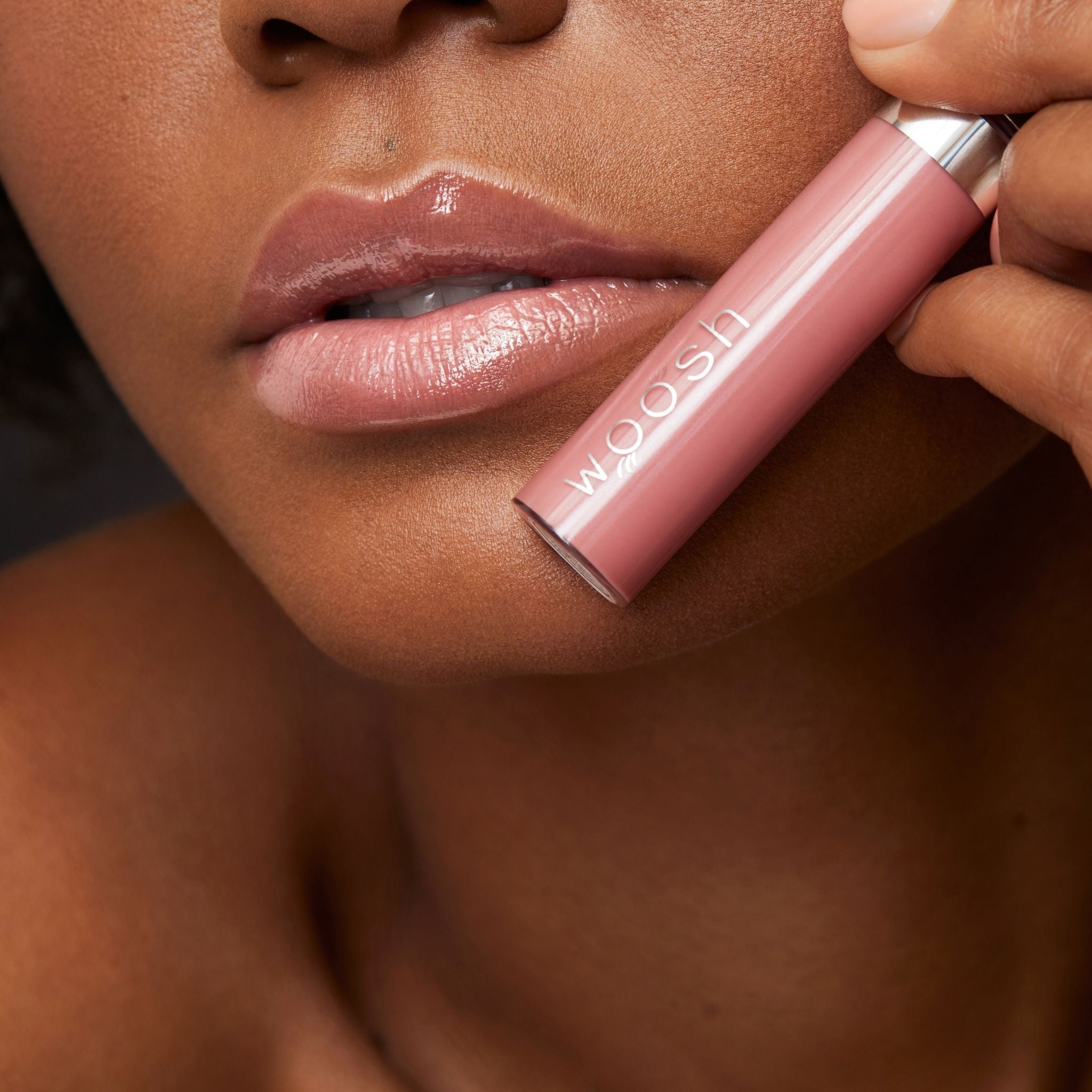Previously known as beige natural, hint is now infused with shea butter and hyaluronic acid. The perfect nude light pink shade. Photo of model holding bottle close to lip.