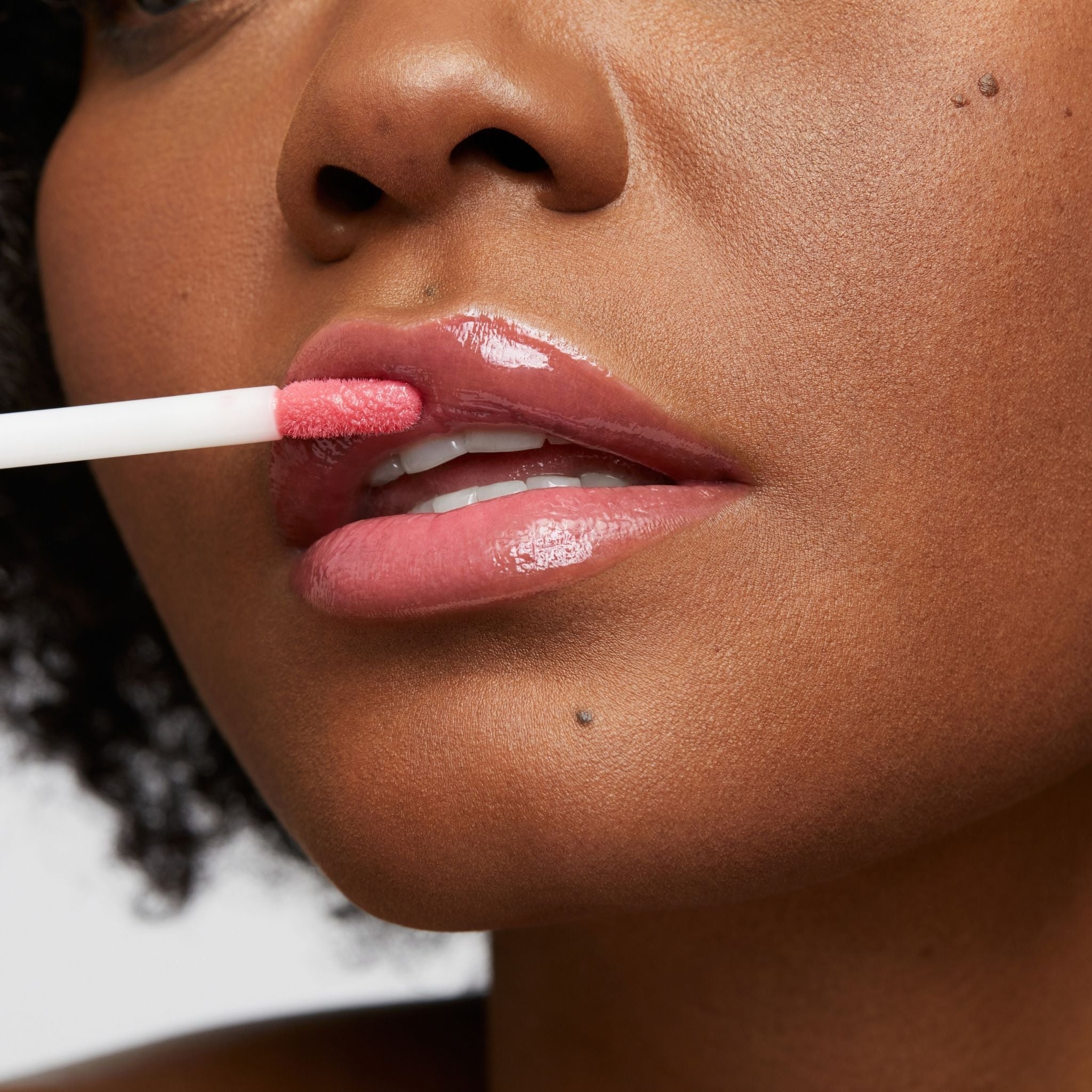 Previously known as pink natural, pop is now infused with shea butter and hyaluronic acid. The perfect pink pop of color shade. Photo of model applying gloss to lip 