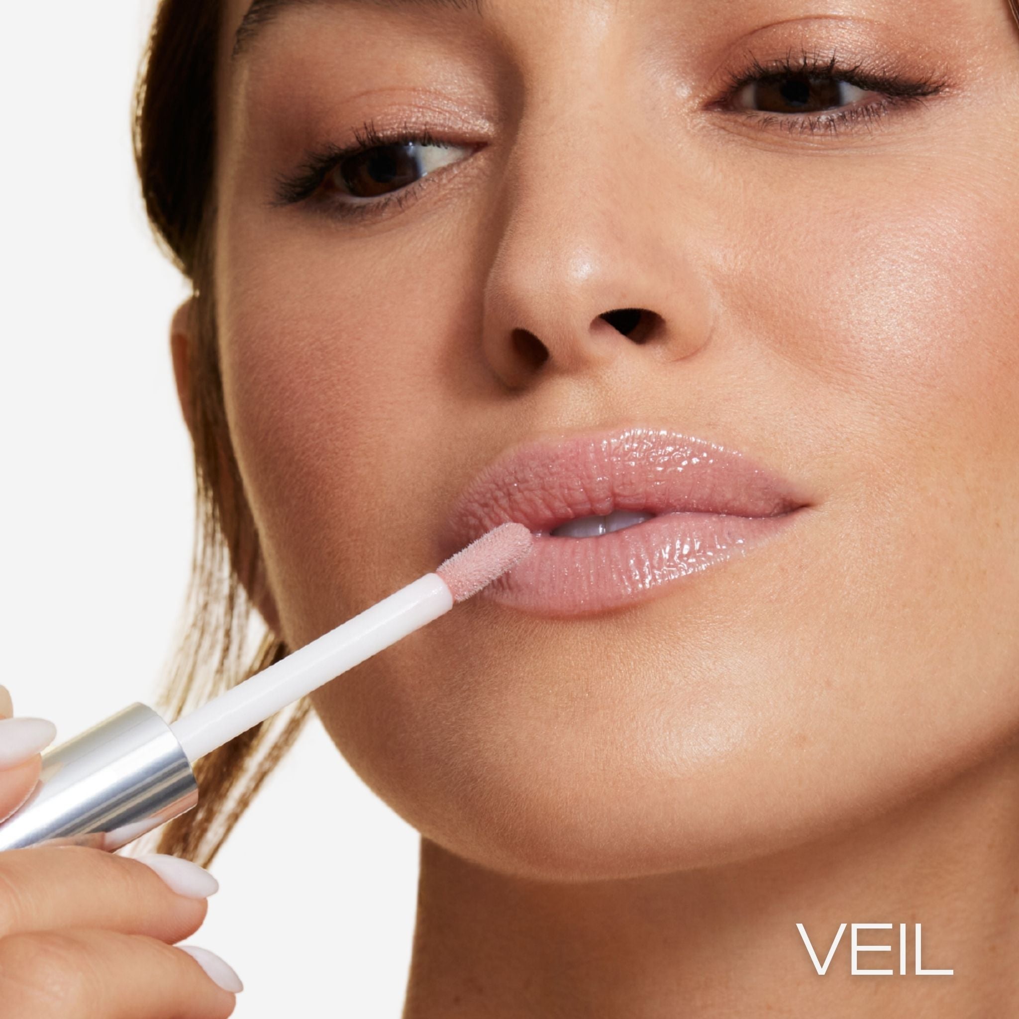 Previously known as beige frosted, our favorite lip gloss has been renamed to veil. Now infused with shea butter AND hyaluronic acid. Photo of model applying gorgeous nude color to lips