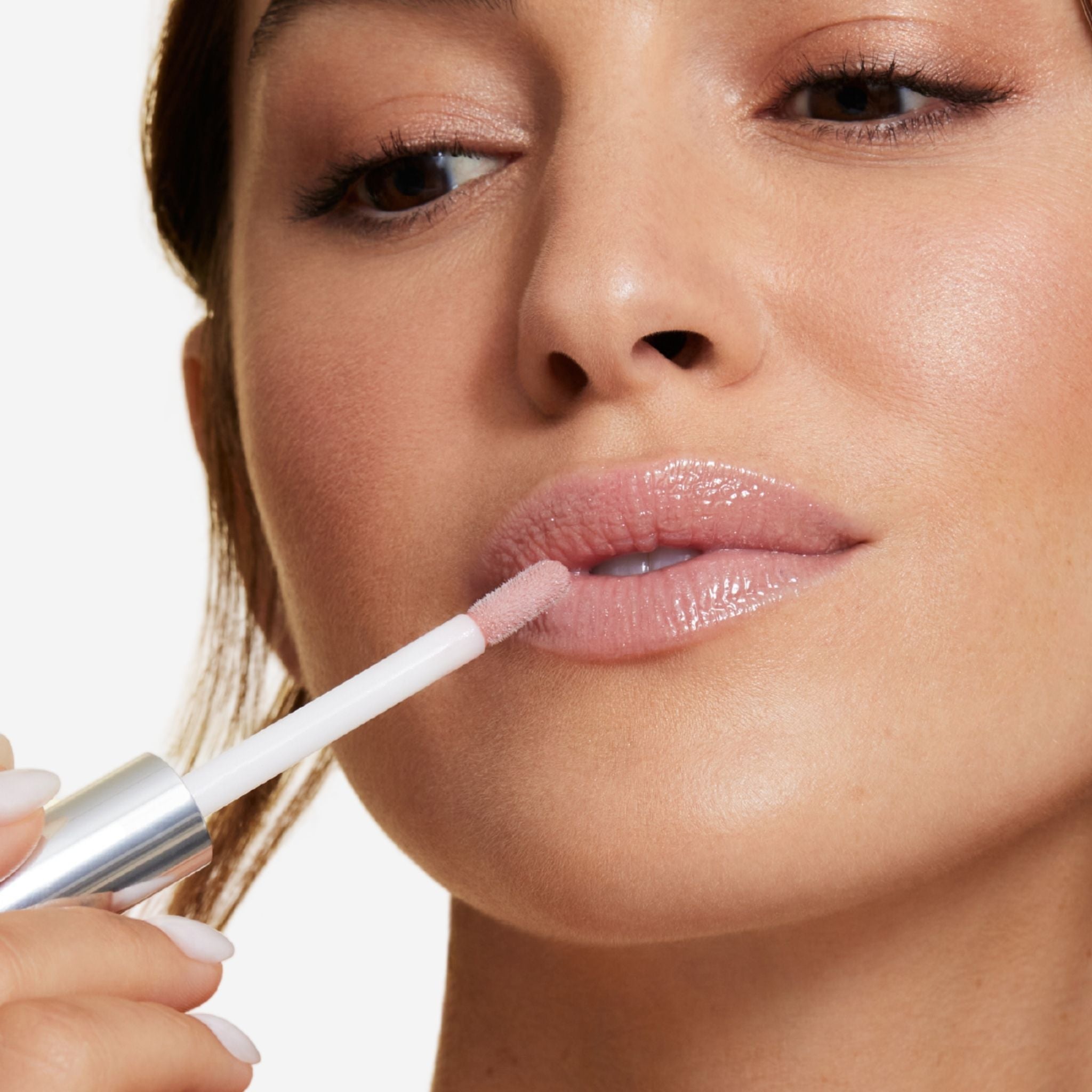 Previously known as beige frosted, our favorite lip gloss has been renamed to veil. Now infused with shea butter AND hyaluronic acid. Photo of model applying gorgeous nude color to lips
