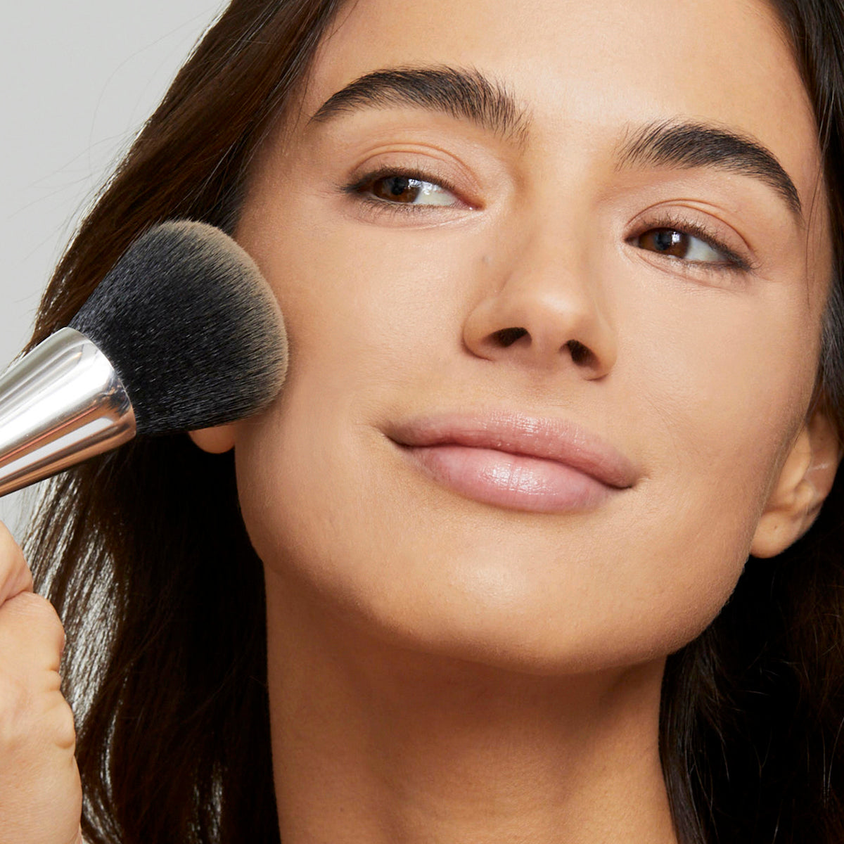 Applying and blending foundation powder with the large end of the Woosh complexion brush