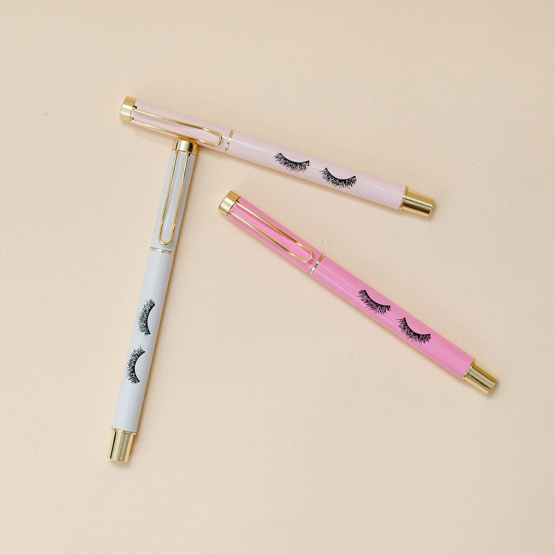 Set of three pens in pink shades (light pink, white, and hot pink) with gold trim and eyelash details