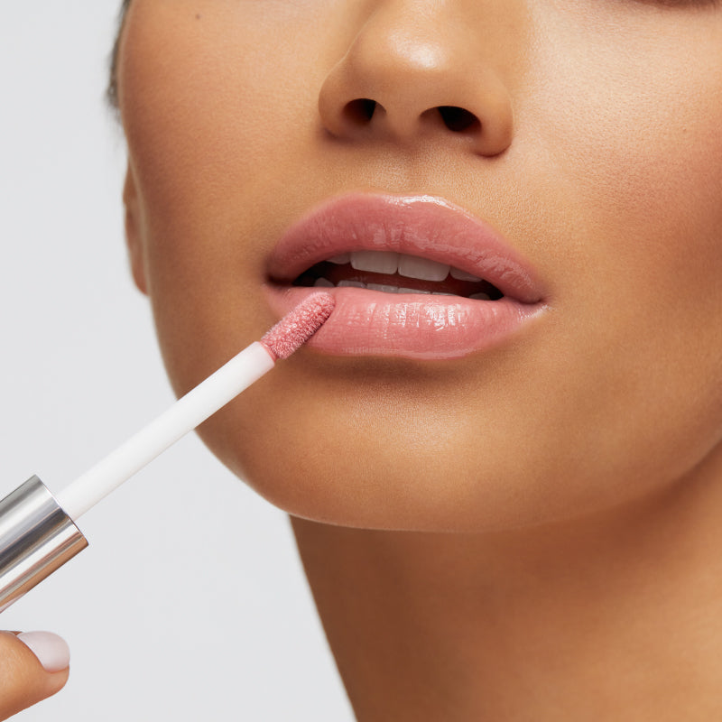 Model applying the beige natural spin on lip gloss to lips