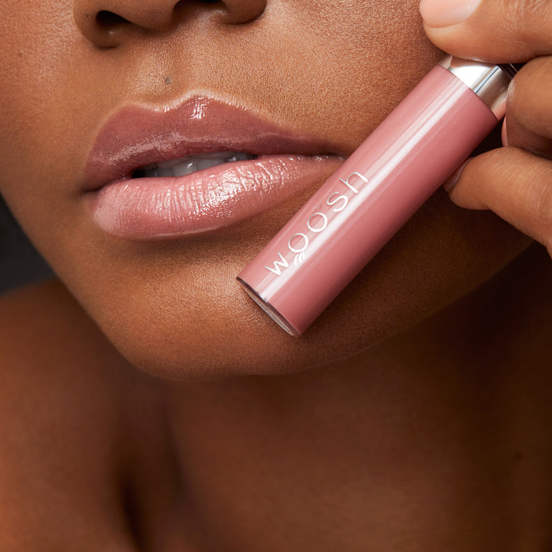 Model holding the beige natural spin on lip gloss against lips