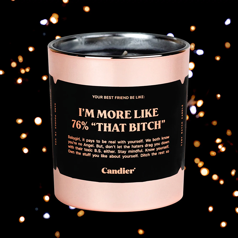 I'm more like 76% that bitch candle with rose gold outer finish and silver inside trim displayed in front of a black background with lights