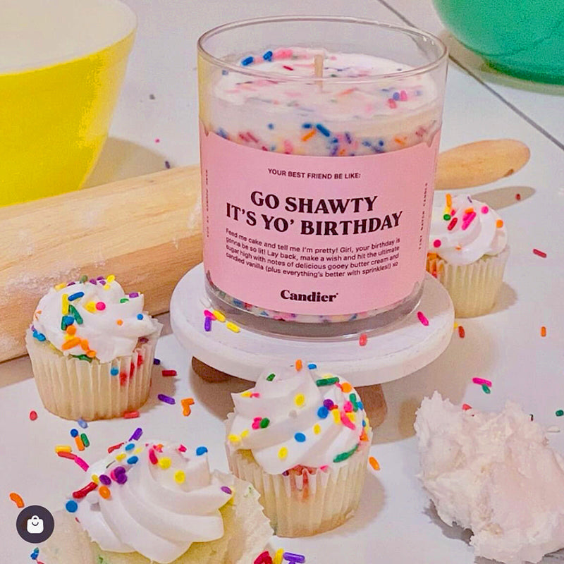 White "Go Shawty It's Yo' Birthday" Candle with sprinkles displayed with decorative cupcakes