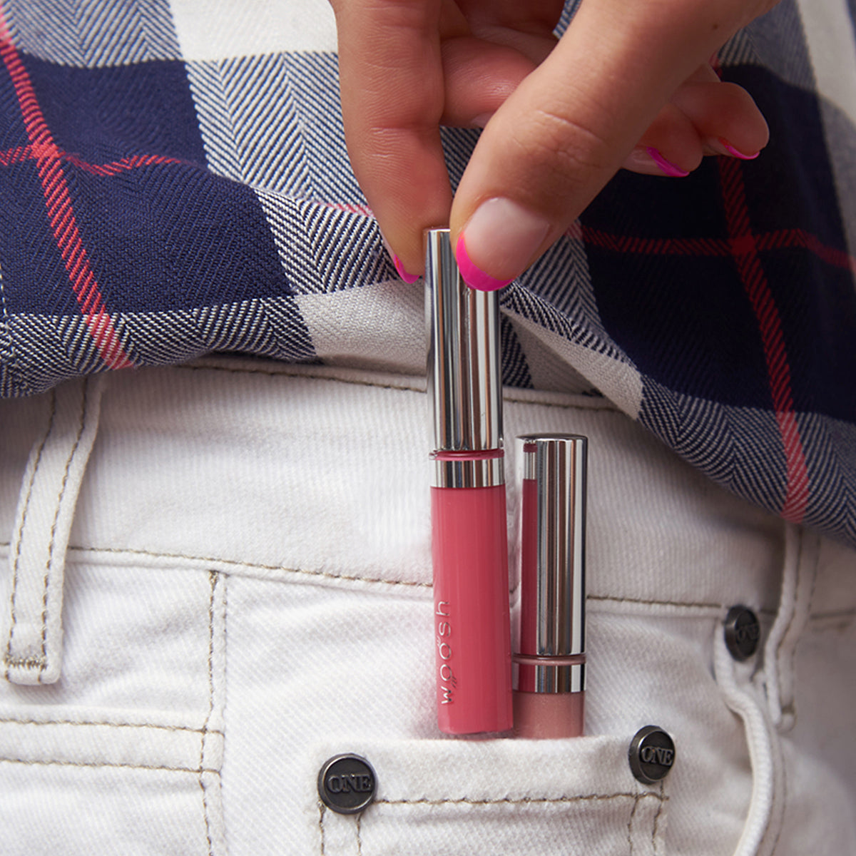Model demonstrating the size of the mini lip gloss by putting both lip glosses in shades beige frosted and pink natural in small jean pocket