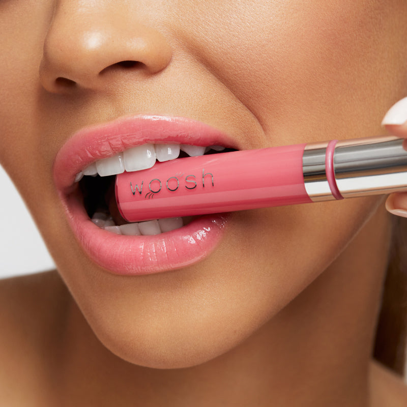 Model biting the pink natural spin on lip gloss